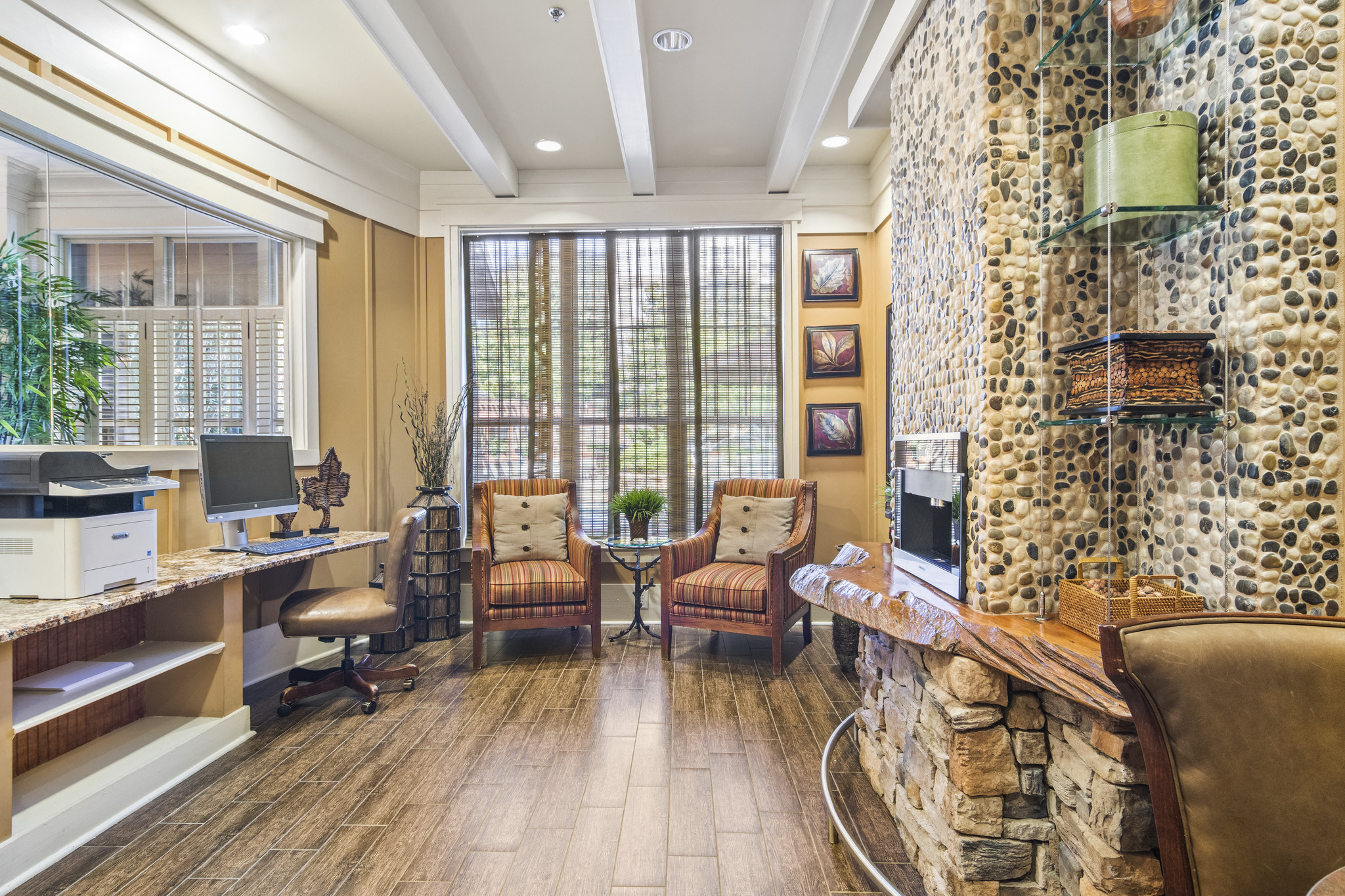 a living room with a stone fireplace and a desk with chairs