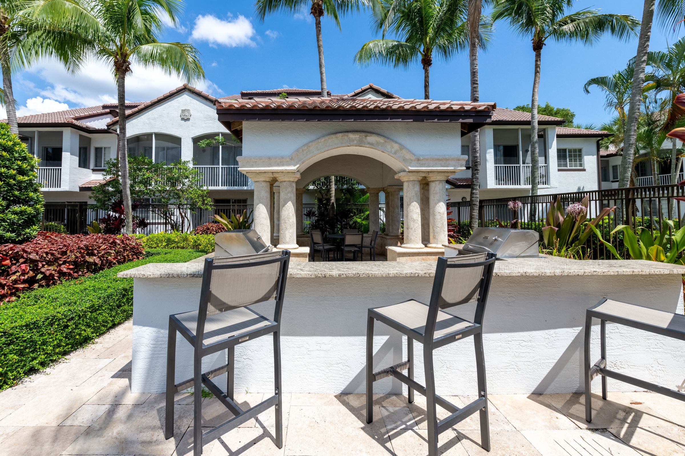 a patio with two chairs in front of a pool