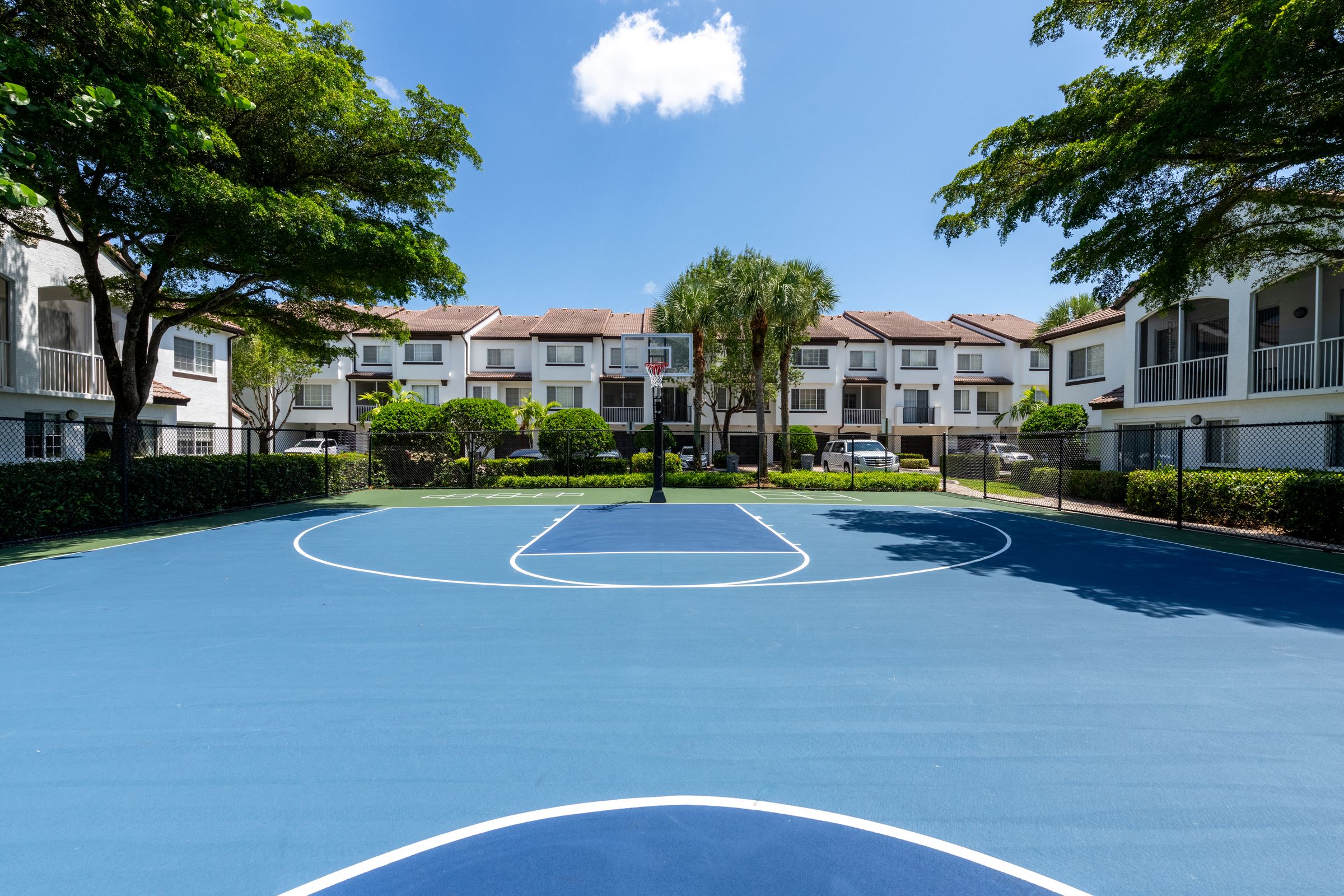 a blue basketball court with apartments in the background