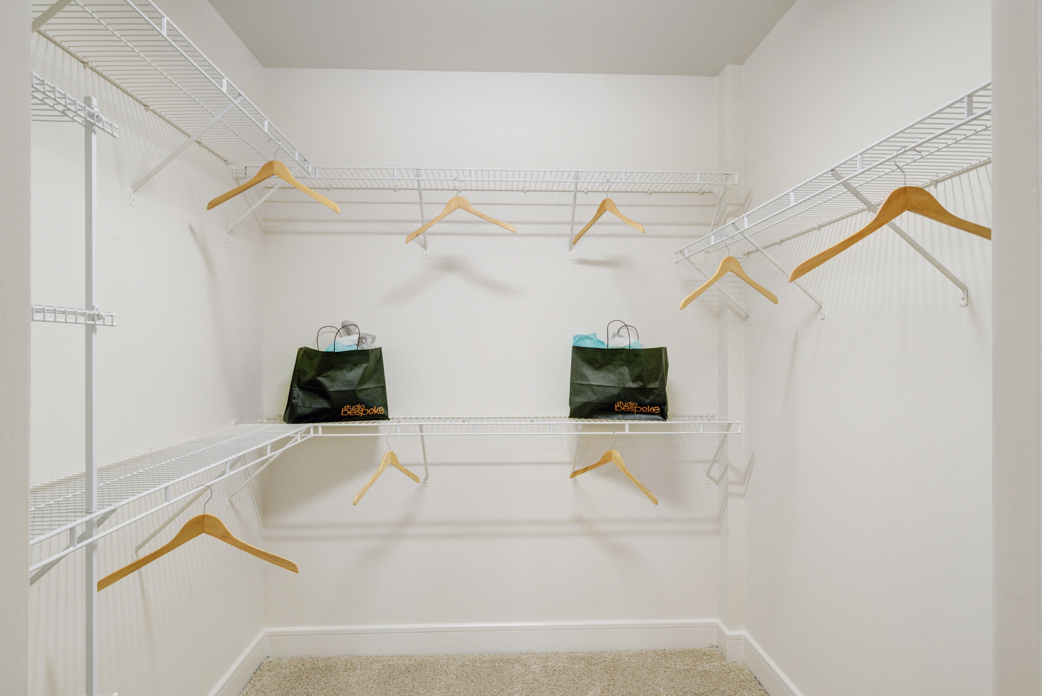 a spacious closet with white walls and shelves and bags on racks