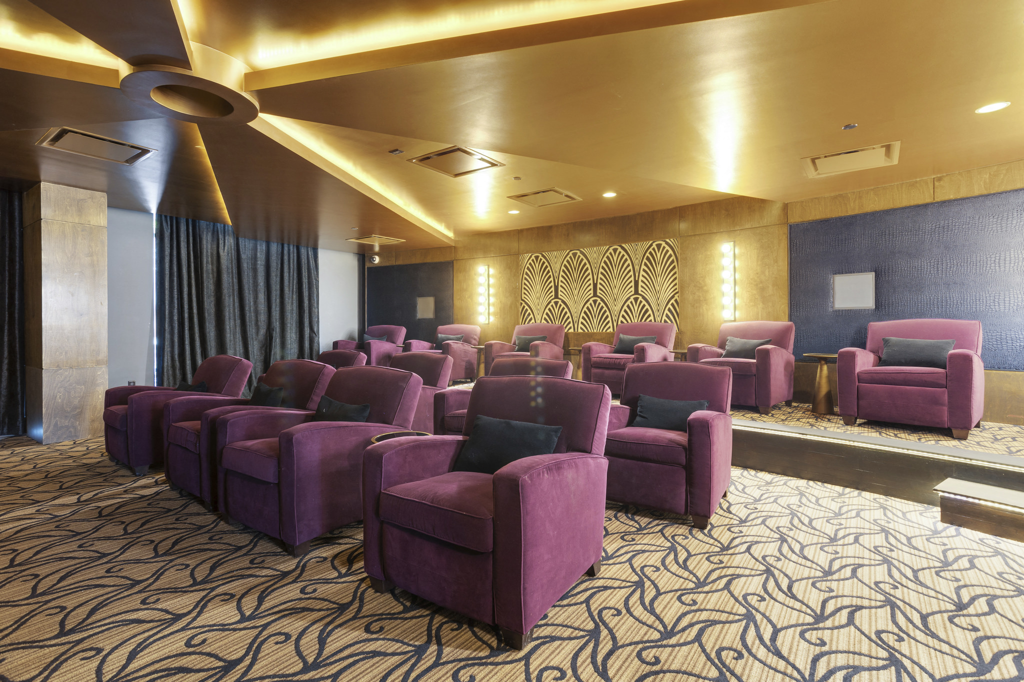 a theater room with purple chairs and a carpet