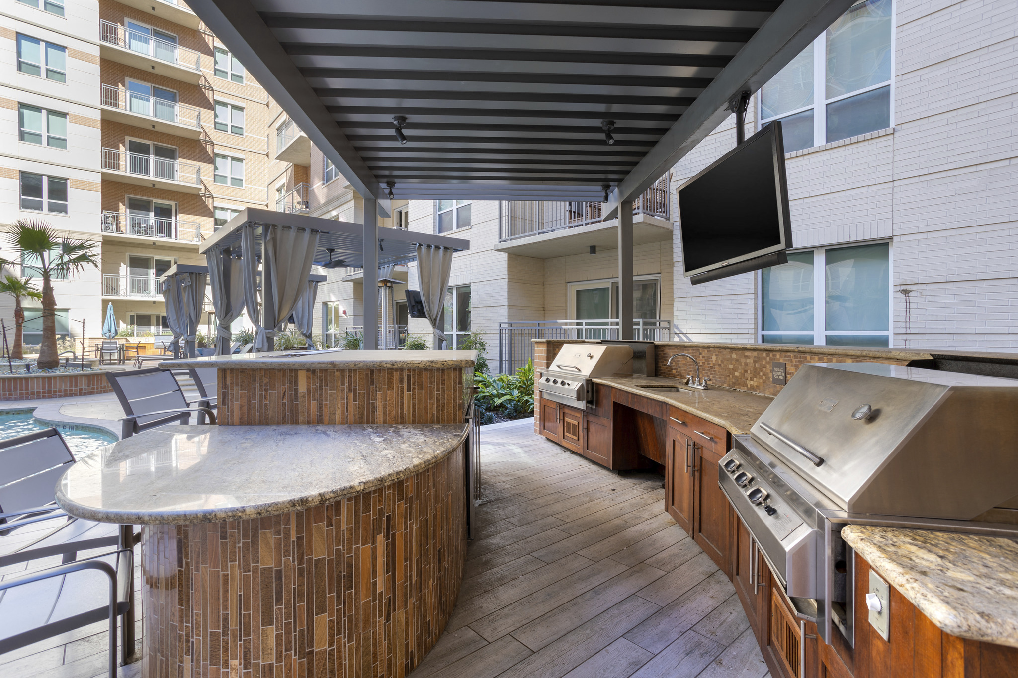 a patio with a grill and a bar and a television