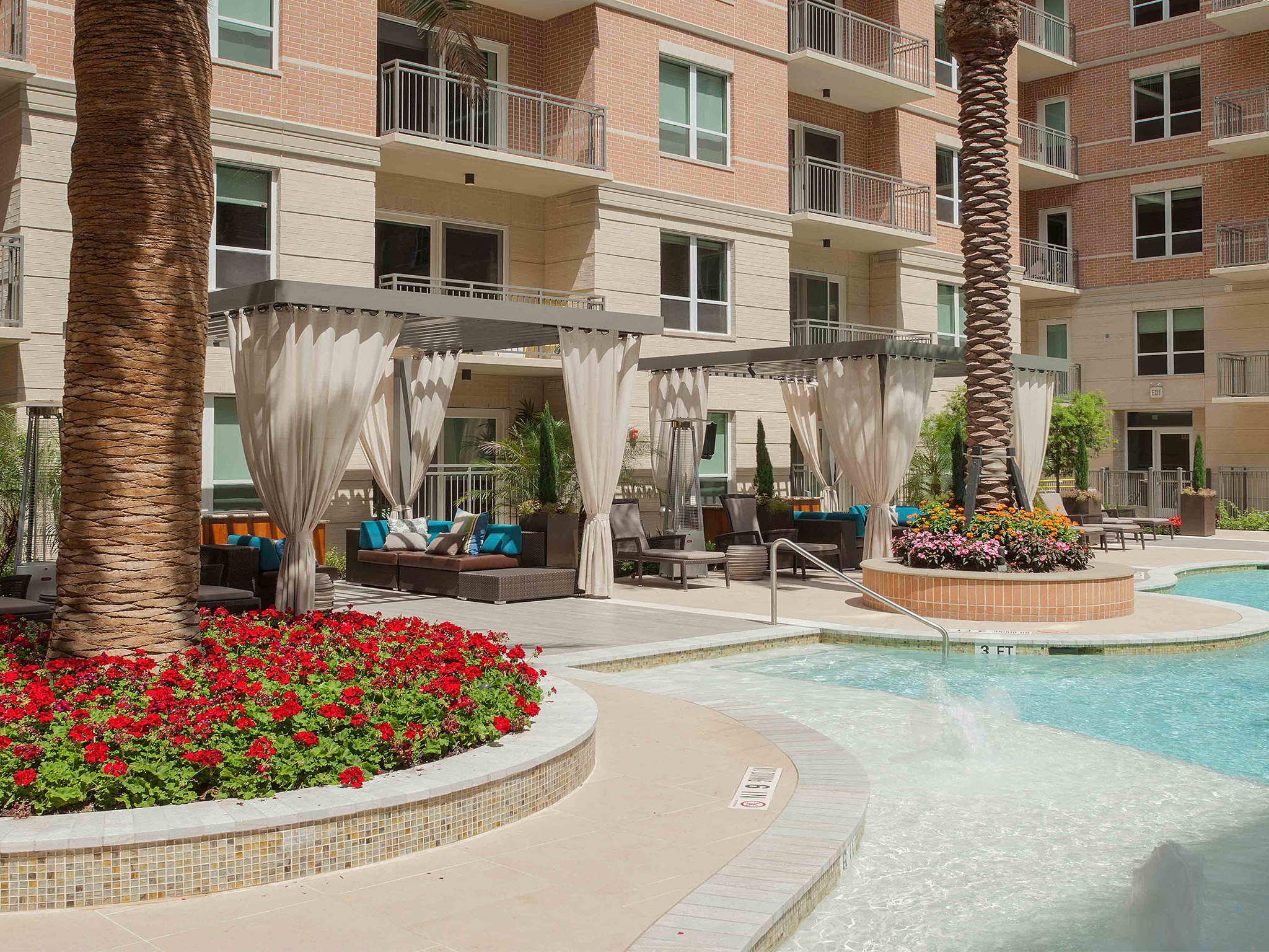 a swimming pool in front of a building with palm trees