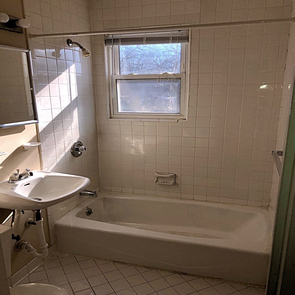 a bathroom with a tub and a sink and a window