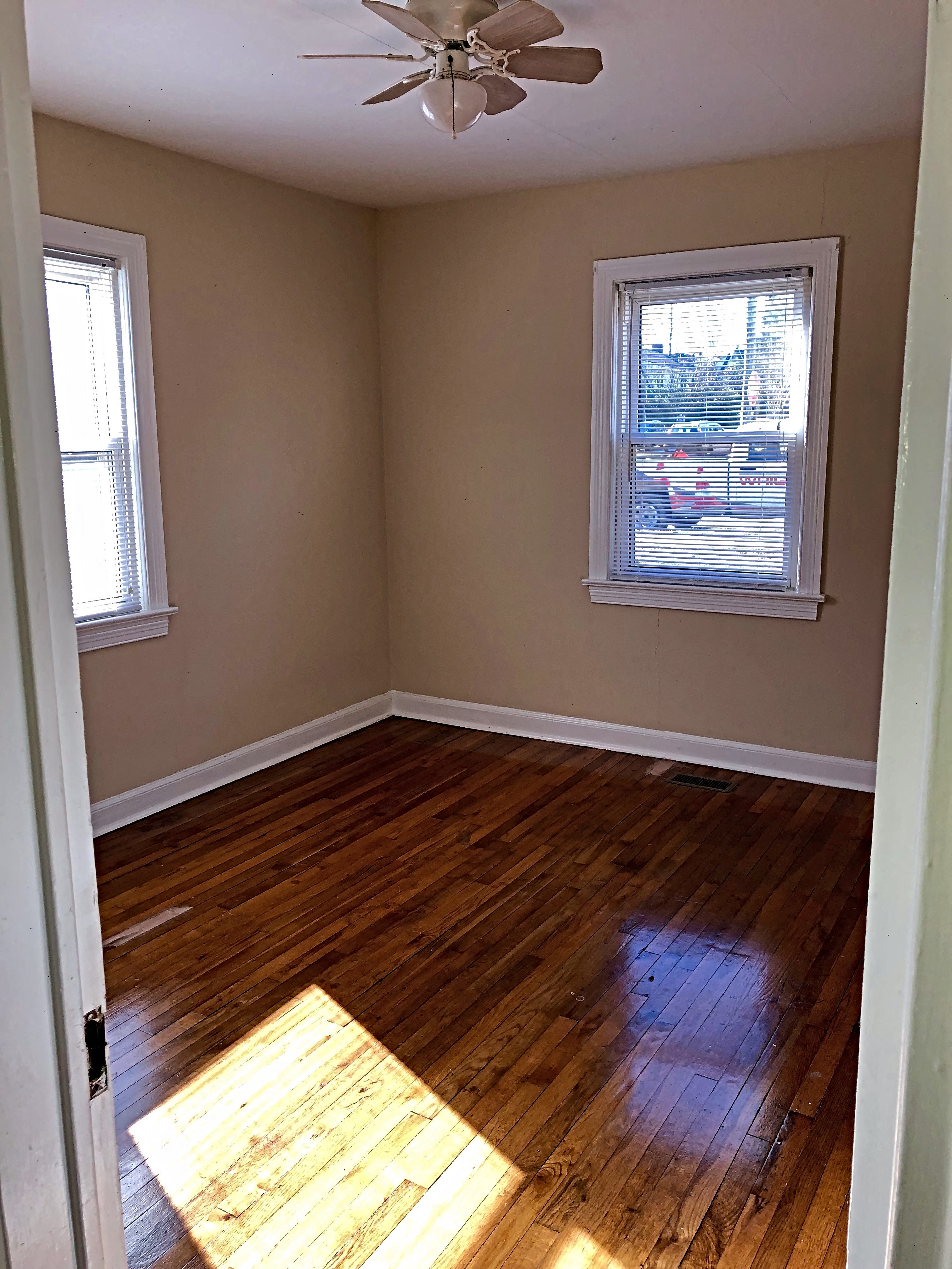 an empty room with wooden floors and a ceiling fan