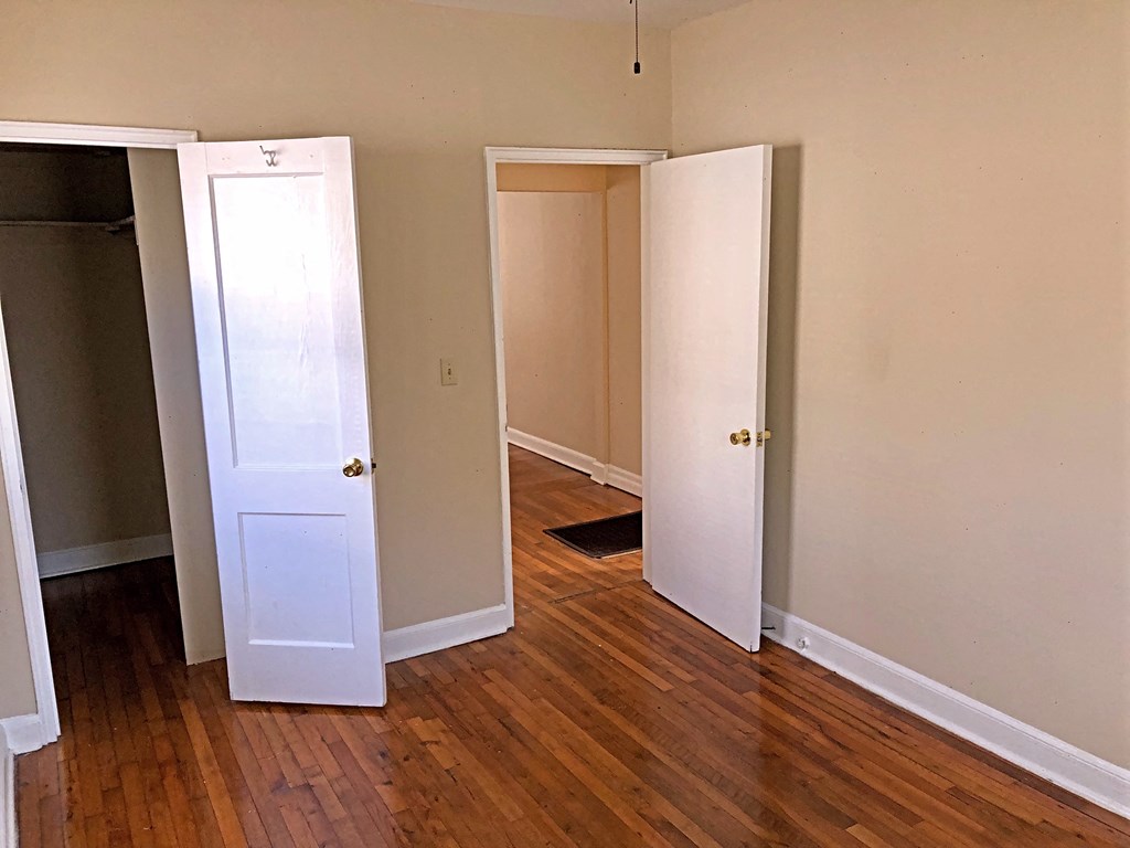 an empty bedroom with three doors and a wood floor