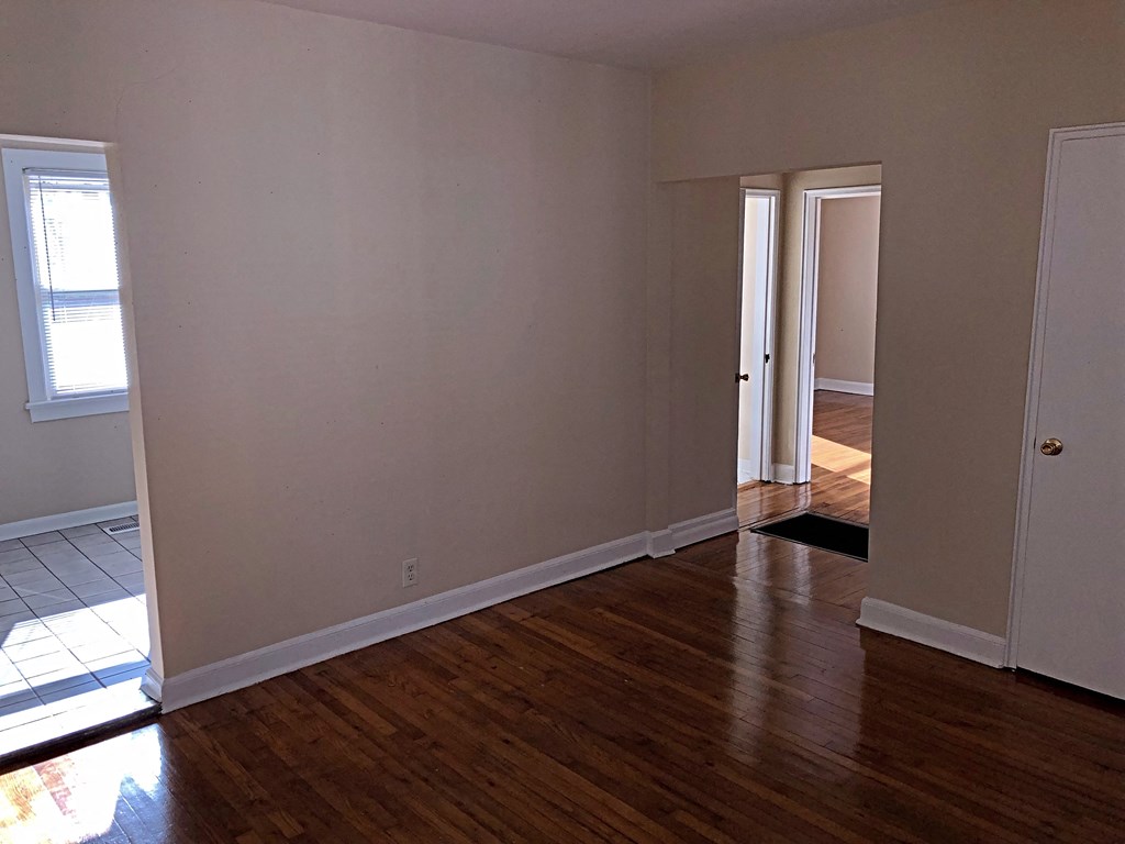 a living room with wooden floors and a door to a hallway