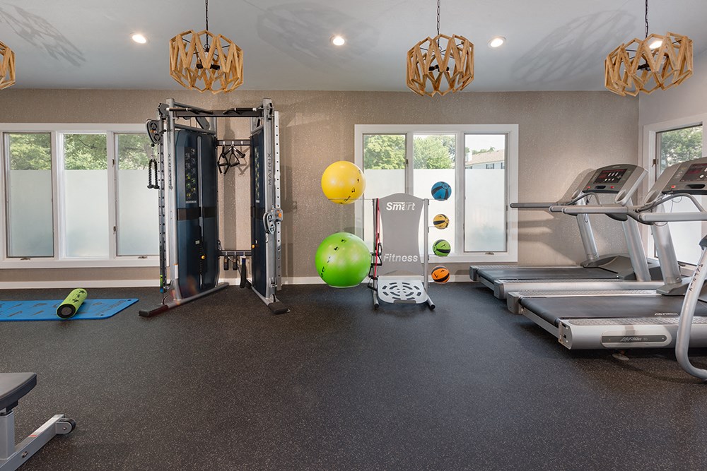 a gym with treadmills and weights and a ball on the floor