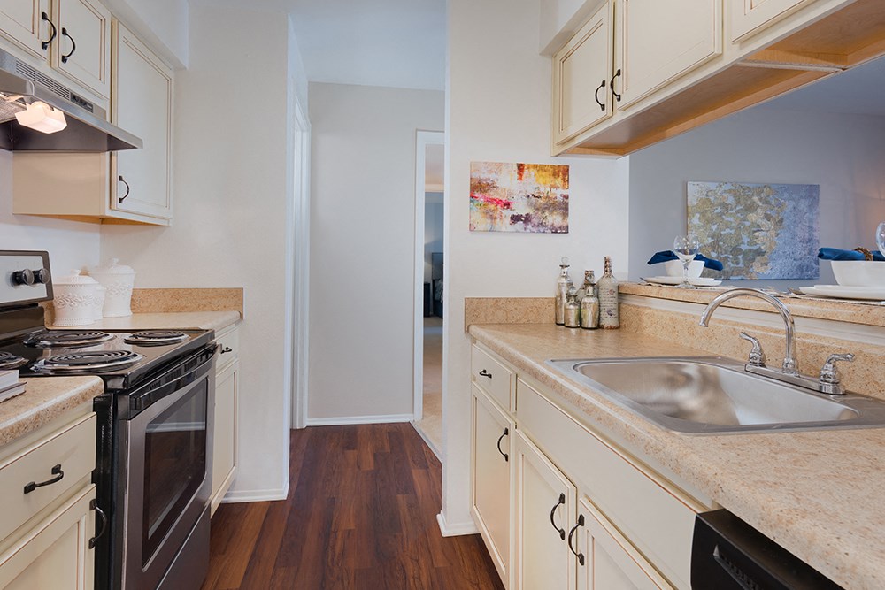 a kitchen with white cabinets and a sink and a stove