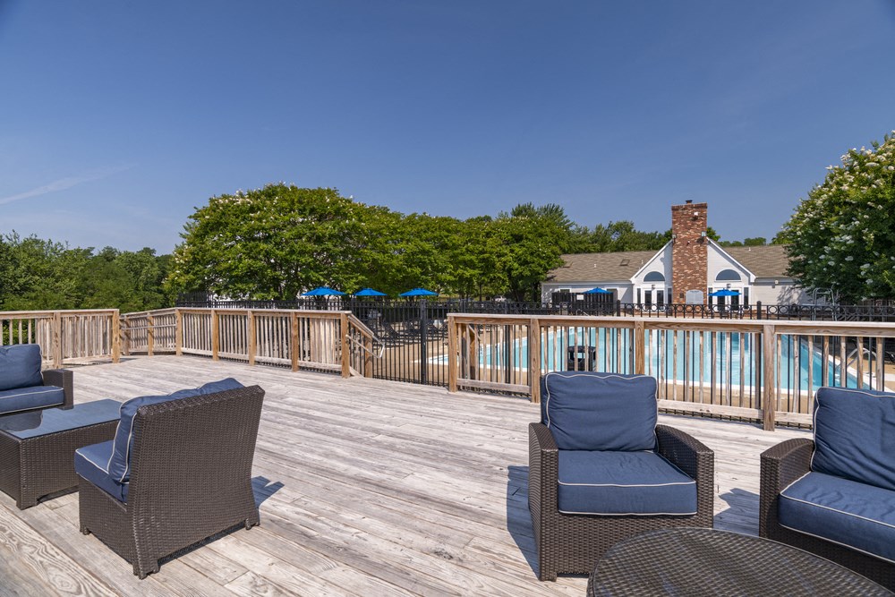 a deck with chairs and a pool with a house in the background