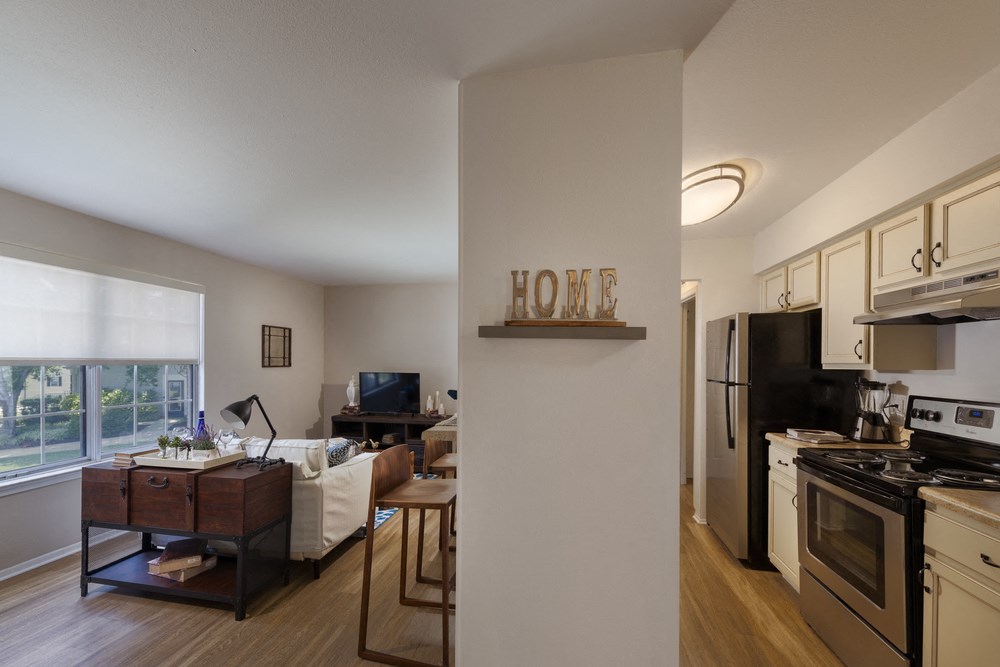 kitchen and living room of an apartment with a home sign on the wall