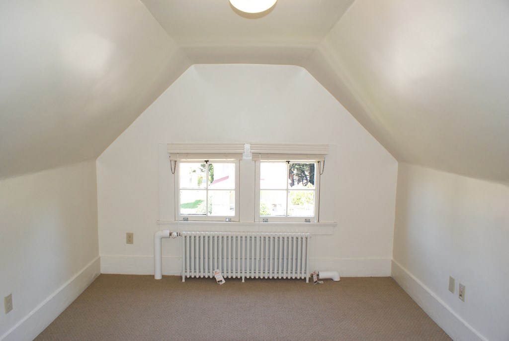 a small attic room with a radiator and a window