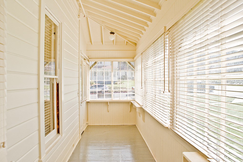 a long hallway with white walls and white blinds and a large window