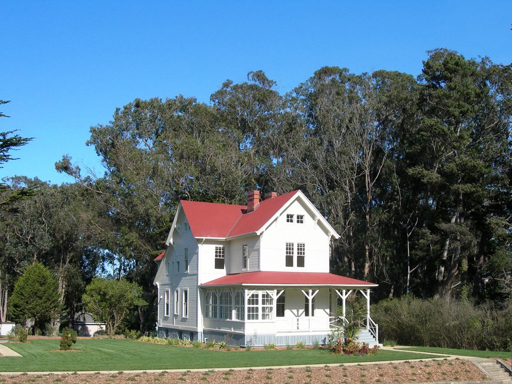 a white house with a red roof on a lawn