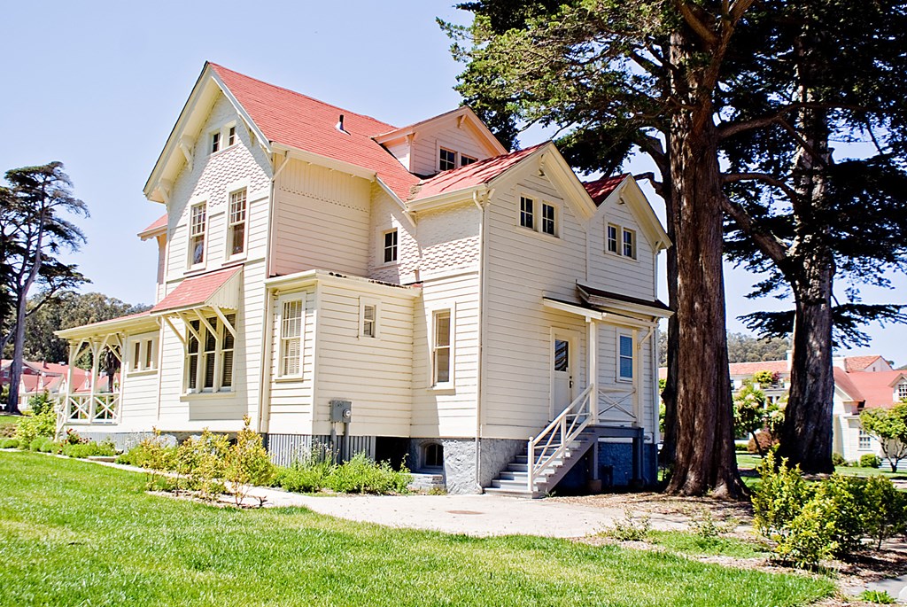 a white house with a red roof and a tree