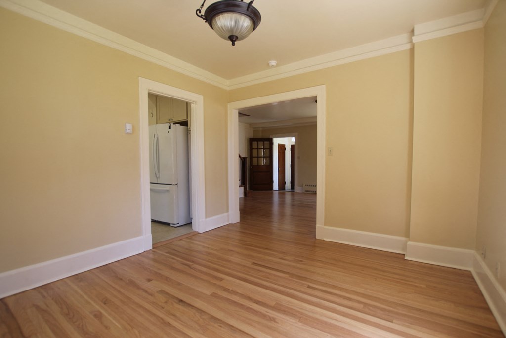 a empty living room with a hard wood floor and a refrigerator