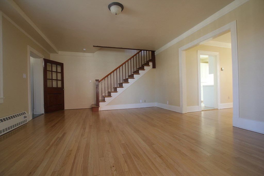 an empty living room with wooden floors and a staircase