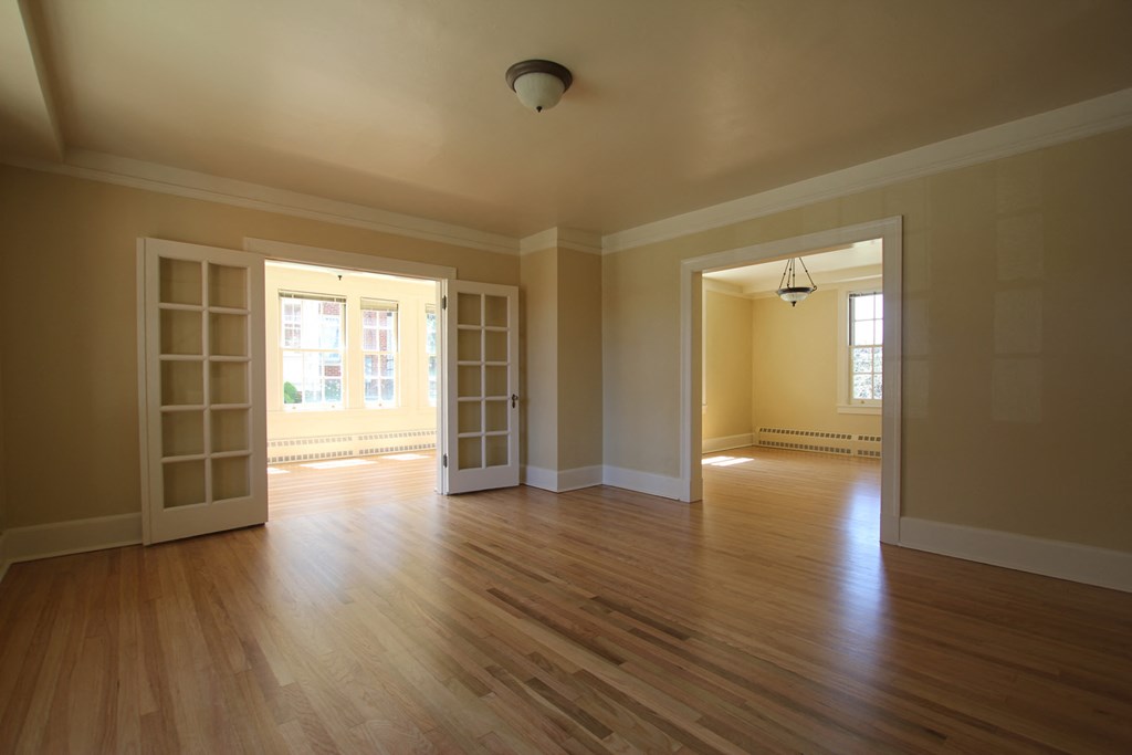 an empty living room with a hard wood floor and open doors
