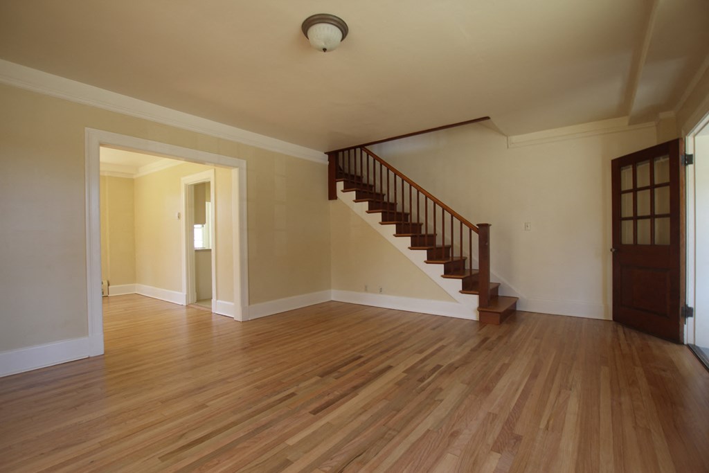 an empty living room with wood floors and a staircase
