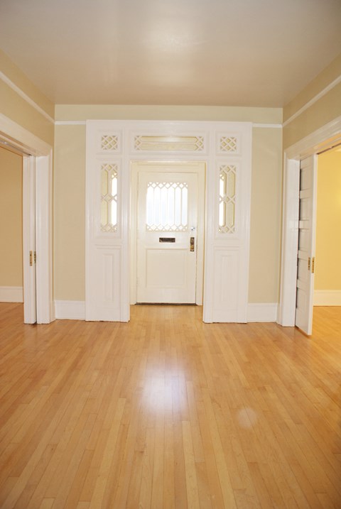 an empty living room with wooden floors and white doors