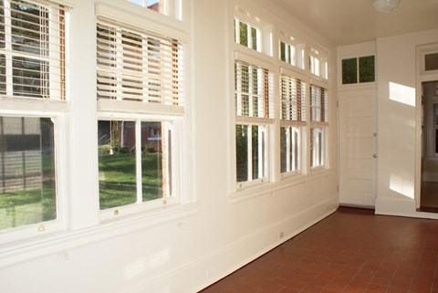 a living room with large windows and a red tile floor