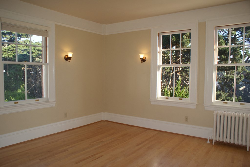 an empty room with three windows and a wooden floor