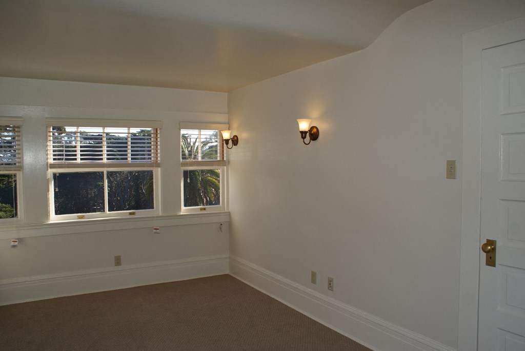 an empty room with a window and a light on the wall