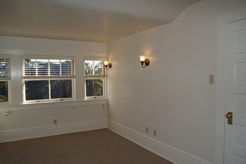 an empty room with a window and a light on the wall