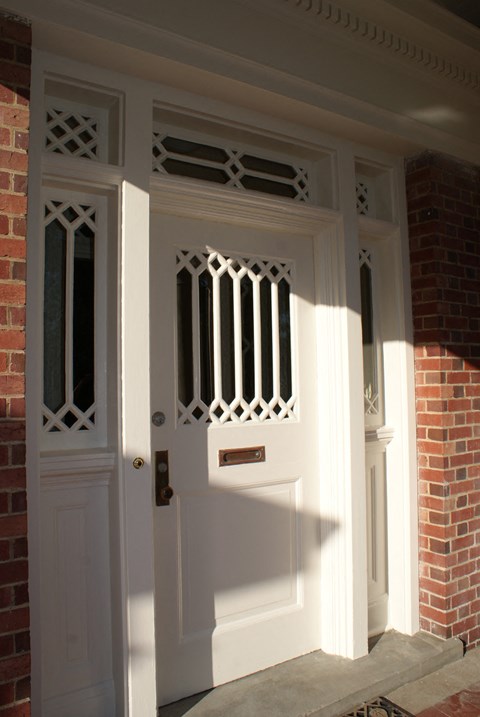 a white porch door with a brick house