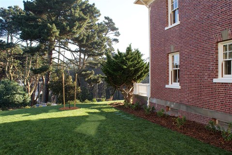 a yard in front of a brick house with grass and trees