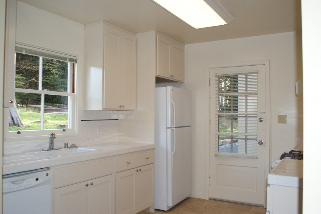 a kitchen with white cabinets and a white refrigerator