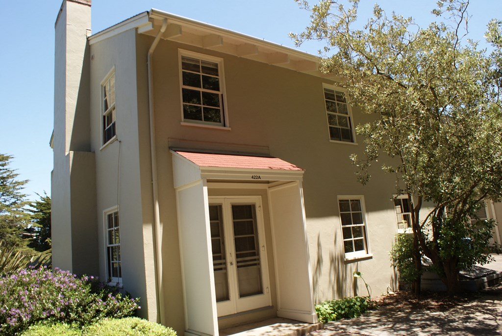 the front of the house is painted beige with white pillars and a red roof