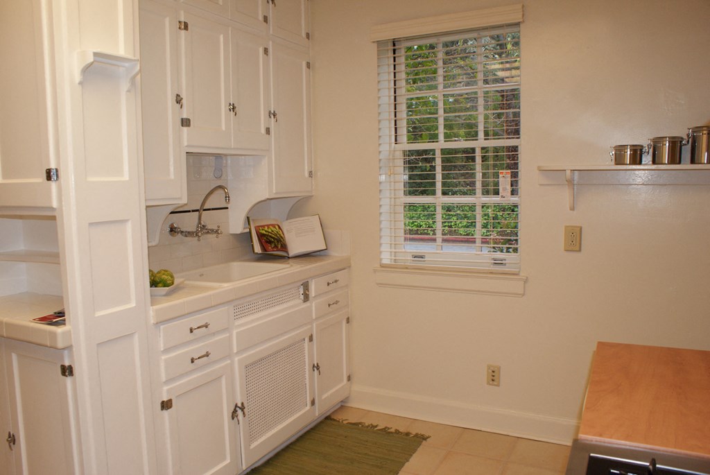 a kitchen with white cabinets and a sink and a window
