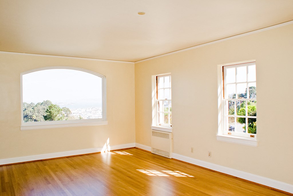 an empty living room with wooden floors and a large window