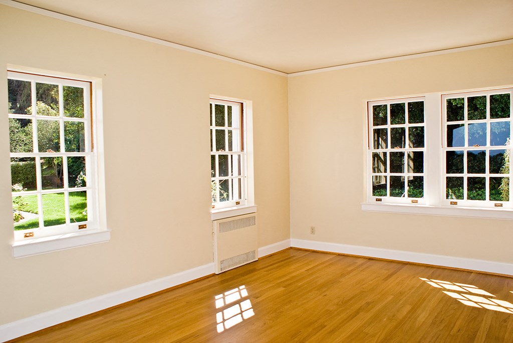 an empty room with three windows and a hardwood floor