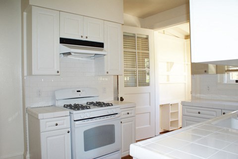 a small kitchen with white cabinets and a white stove and oven
