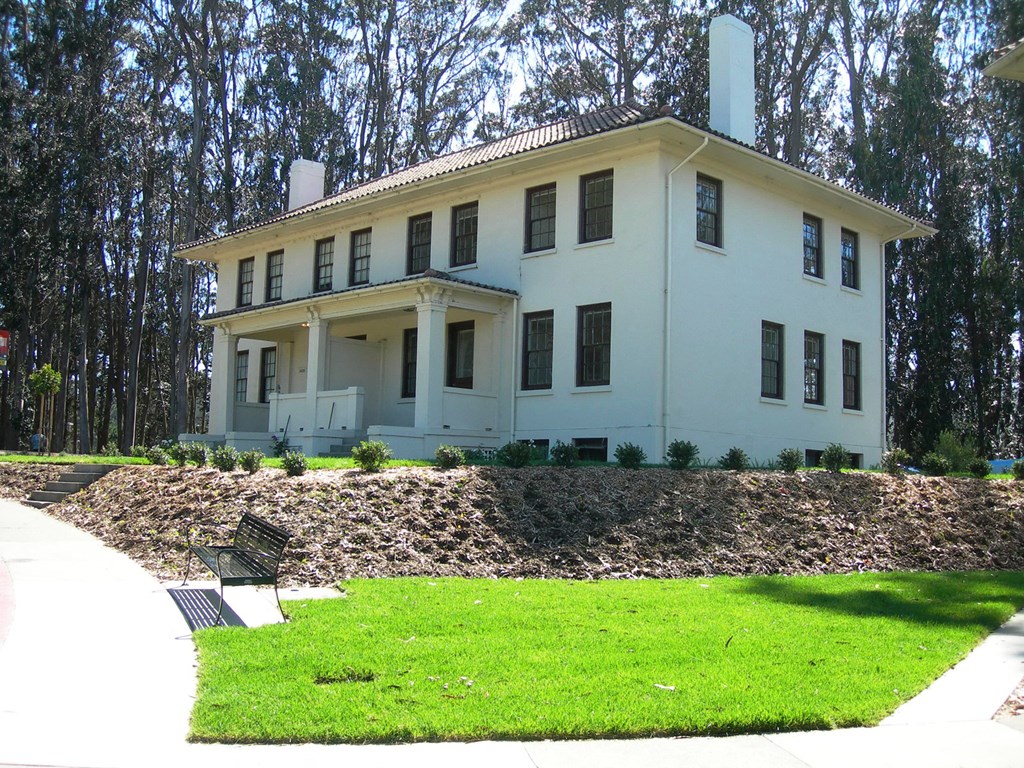 a white house with a lawn and a bench