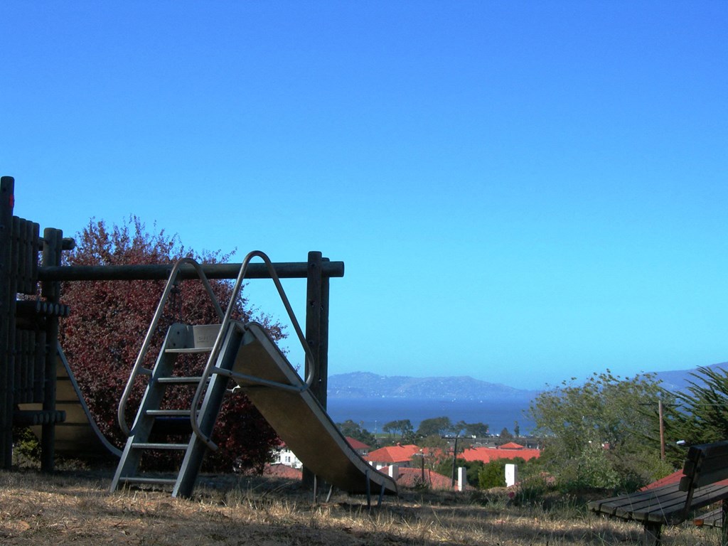 a playground with a slide and a view of the ocean