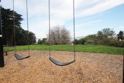 two black swings on a playground in a park
