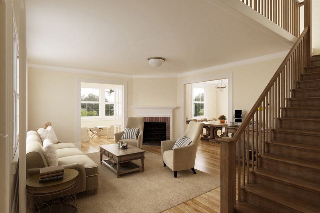 a living room with couches and chairs and a staircase