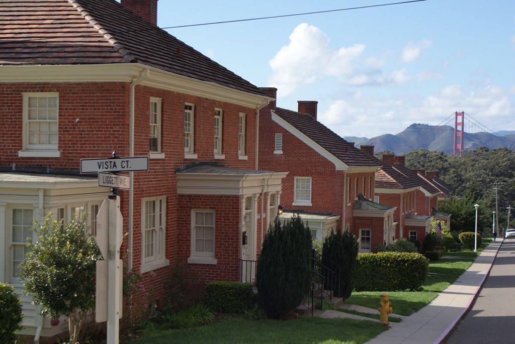 a row of houses on a street with a view of the golden gate bridge