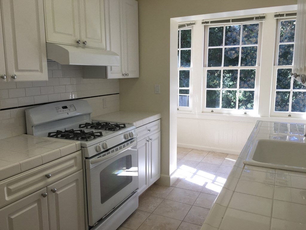 a kitchen with white cabinets and a stove and a sink