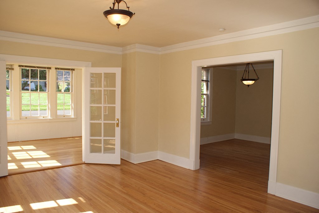 an empty living room with an open door and a hard wood floor