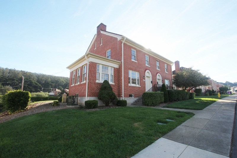 a brick house with a sidewalk in front of it