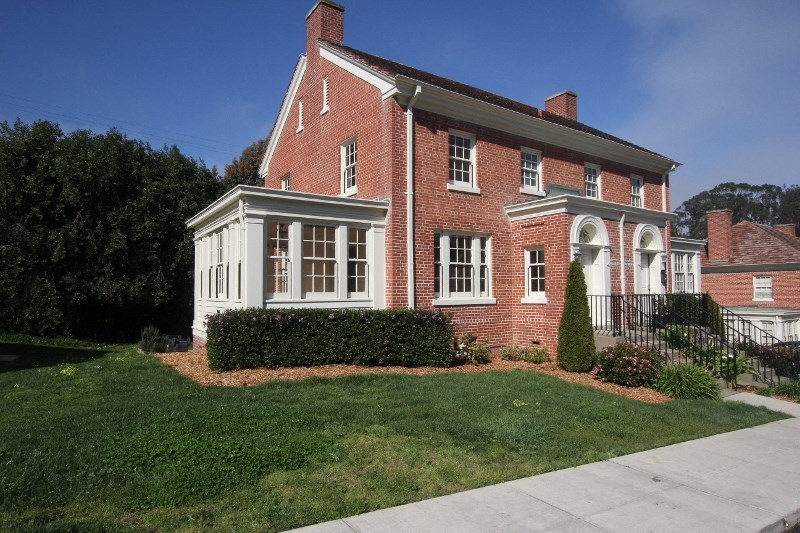 a red brick house with a lawn and a sidewalk