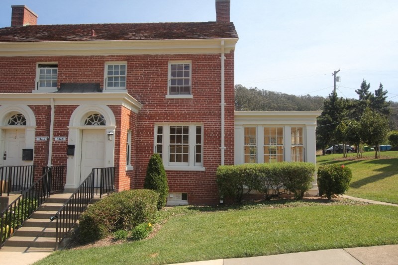 a brick building with a white porch and a lawn