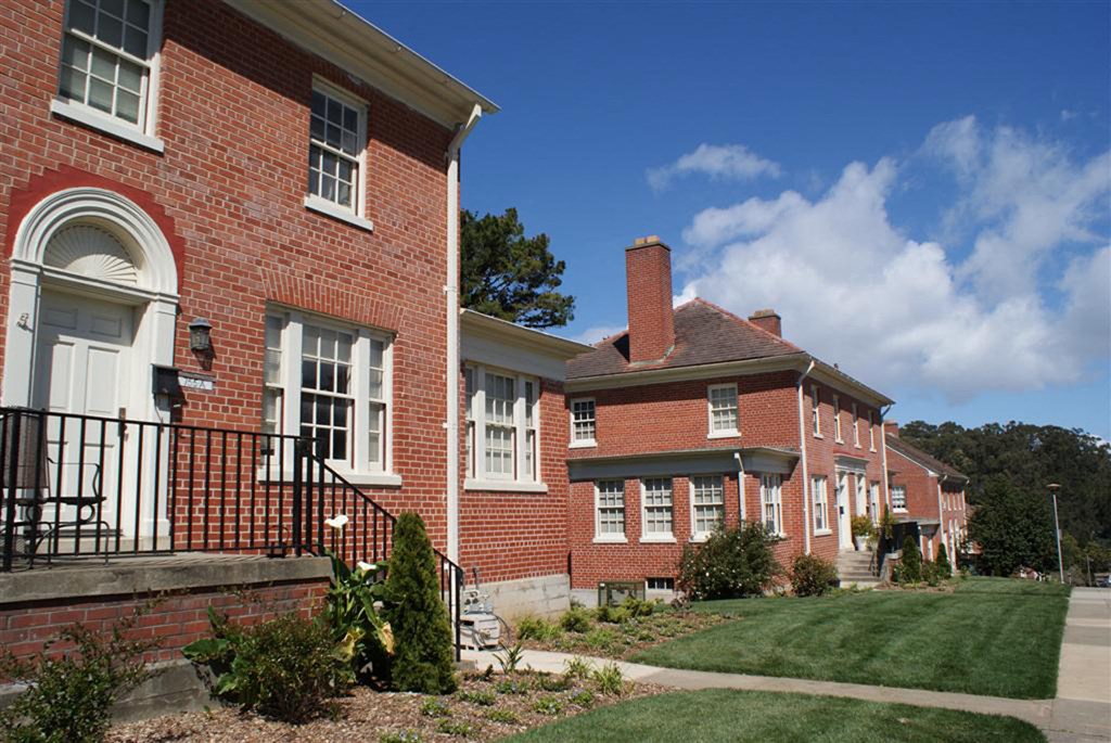 the front and side of a brick building with grass and trees