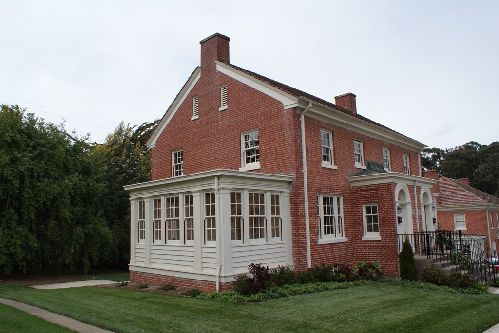 a red brick house with a white porch and a lawn