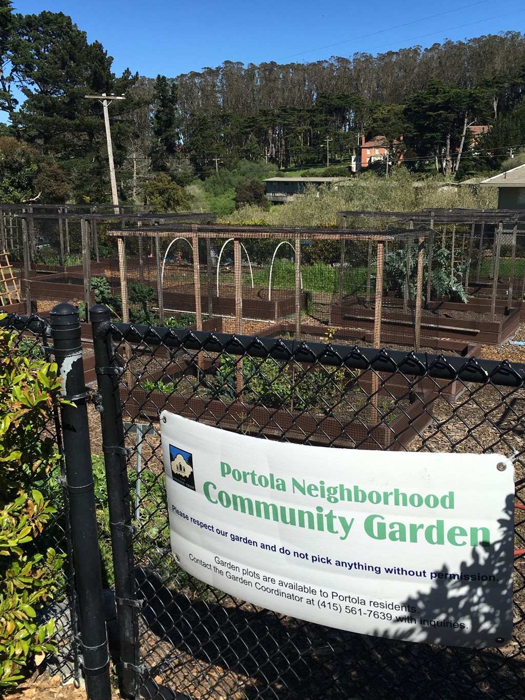 a sign on a fence in front of a community garden