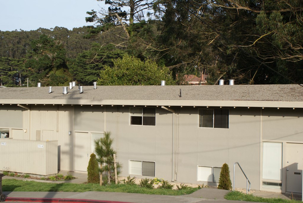 the side of a warehouse building with trees in the background